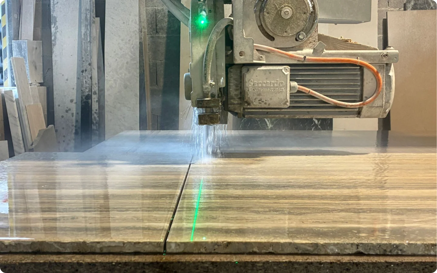 Scie à pont laser découpant précisément une dalle de marbre beige dans l'atelier de notre artisans marbrier.